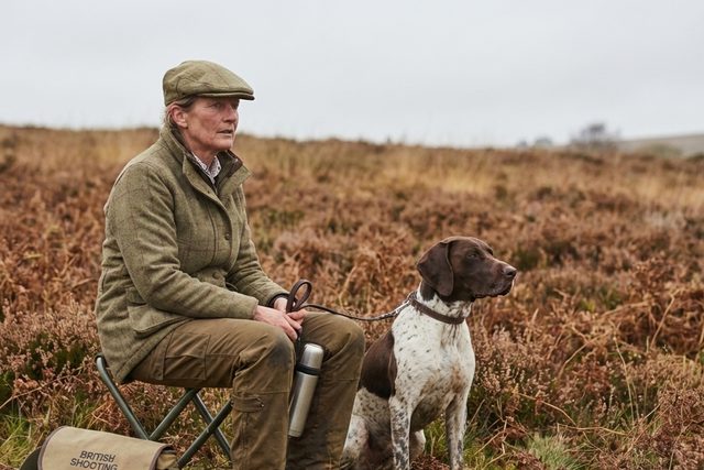 Middle-aged lady happily posing with her German Shorthaired Pointer dog